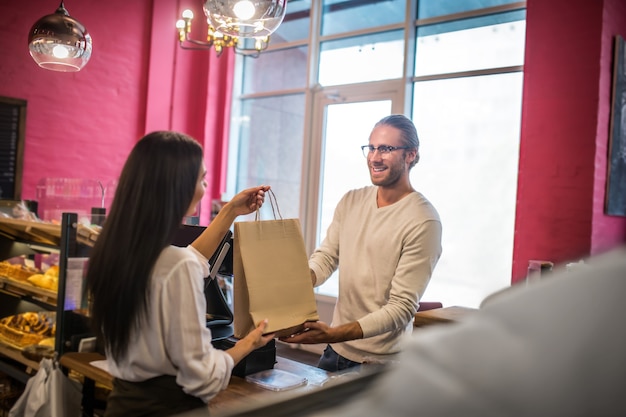 Hombre guapo joven sosteniendo una bolsa de una panadería