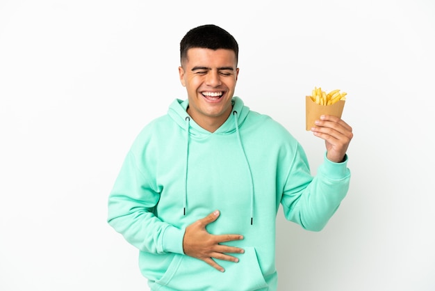 Hombre guapo joven sosteniendo patatas fritas sobre fondo blanco aislado sonriendo mucho
