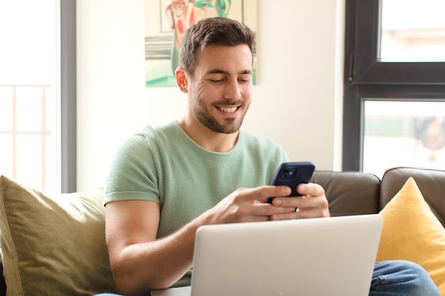 Hombre guapo joven con su teléfono inteligente en casa