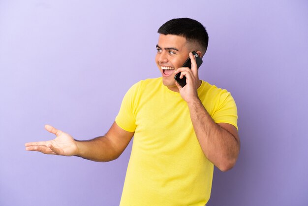 Hombre guapo joven con teléfono móvil sobre fondo púrpura aislado con expresión de sorpresa mientras mira de lado