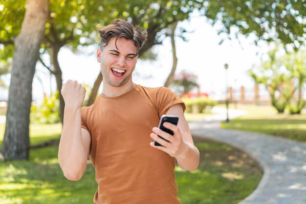 Hombre guapo joven con teléfono en posición de victoria