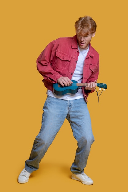 Hombre guapo joven tocando el ukelele