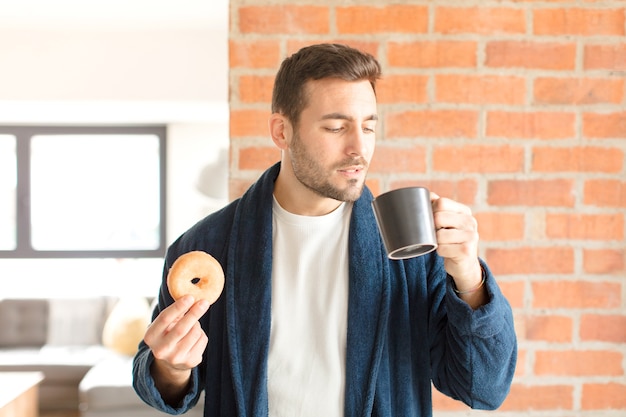 Hombre guapo joven tomando un café en casa