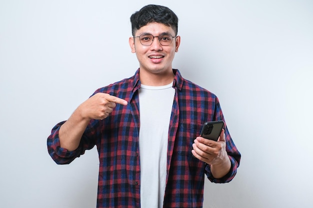 Hombre guapo joven usando teléfono inteligente muy feliz señalando con la mano y el dedo