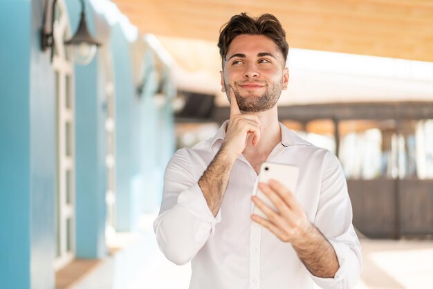 Foto hombre guapo joven usando teléfono móvil y pensando