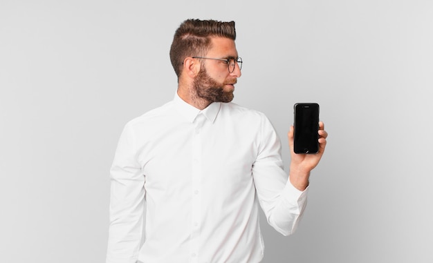 Hombre guapo joven en vista de perfil pensando, imaginando o soñando despierto y sosteniendo una celda