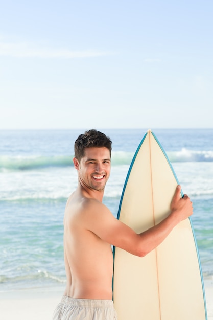 Hombre guapo junto al mar con su tabla de surf