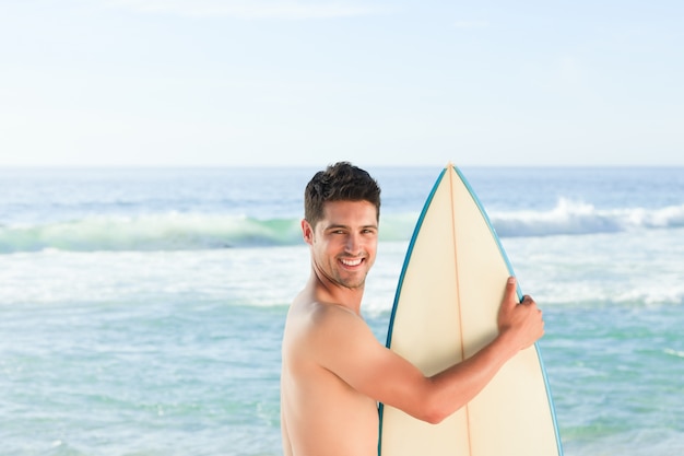 Hombre guapo junto al mar con su tabla de surf