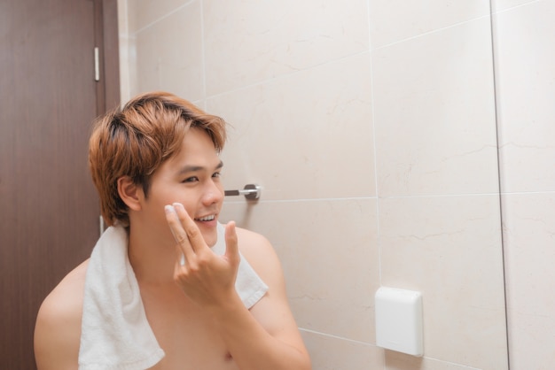 Hombre guapo lavándose la cara en el baño.