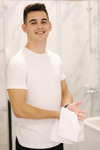 Hombre guapo se limpia las manos con una toalla blanca después de lavar el baño ligero mantener el concepto limpio