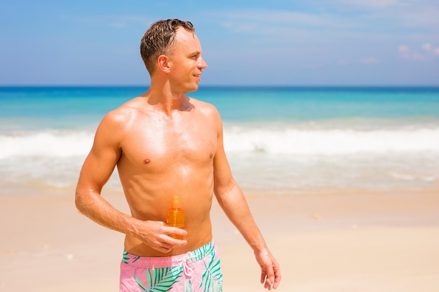 Foto hombre guapo con loción de protección solar en la playa