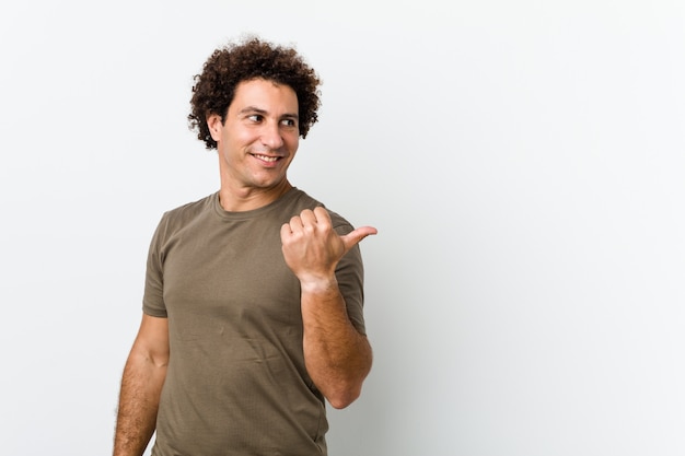 Foto hombre guapo maduro aislado puntos con el dedo pulgar, riendo y despreocupado.