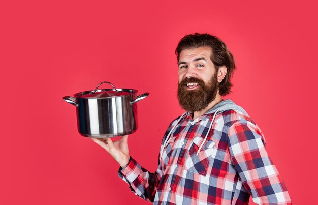 Hombre guapo maduro en camisa a cuadros sostenga la sartén para cocinar la cena