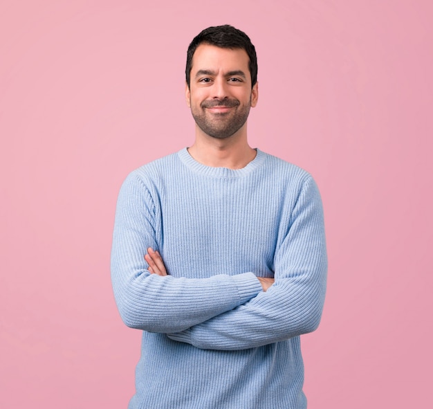 Hombre guapo manteniendo los brazos cruzados sobre fondo rosa