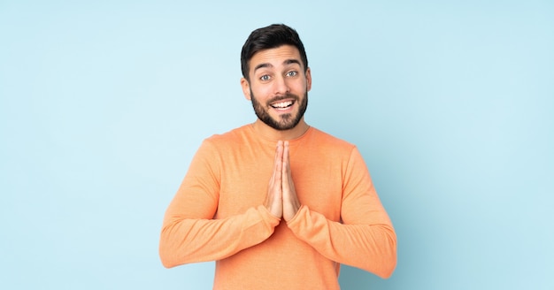 hombre guapo mantiene la palma de la mano. La persona pide algo sobre azul