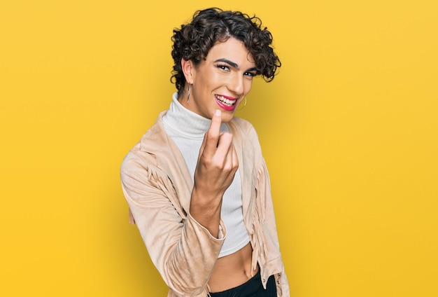 Hombre guapo con maquillaje y ropa de mujer llamando ven aquí gesto con la mano invitando a dar la bienvenida feliz y sonriente