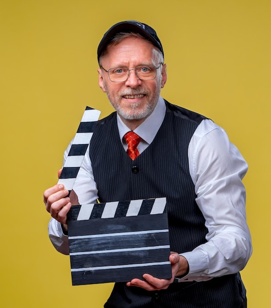 Foto hombre guapo mayor sosteniendo un badajo de cine hombre vestido con traje sin chaqueta persona aislada contra el fondo amarillo