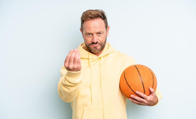 Hombre guapo de mediana edad haciendo capice o gesto de dinero, diciéndole que pague. concepto de baloncesto