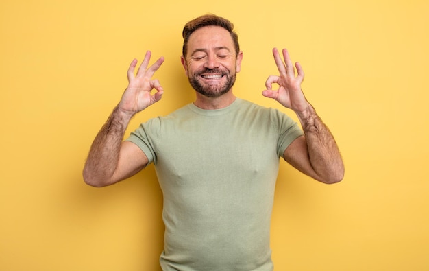 Hombre guapo de mediana edad que parece concentrado y meditando, sintiéndose satisfecho y relajado, pensando o haciendo una elección