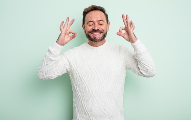 Hombre guapo de mediana edad que parece concentrado y meditando, sintiéndose satisfecho y relajado, pensando o tomando una decisión