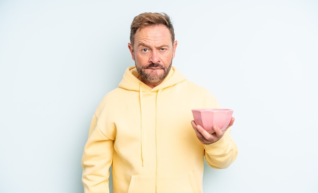 Hombre guapo de mediana edad que parece desconcertado y confundido. concepto de cuenco vacío