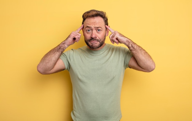 Hombre guapo de mediana edad que se siente confundido o dudando de concentrarse en una idea pensando mucho buscando copiar el espacio al costado