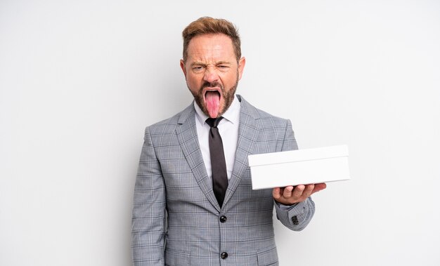 Hombre guapo de mediana edad que se siente disgustado e irritado y con la lengua fuera. concepto de paquete blanco