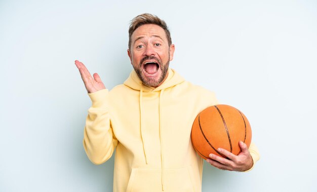 Hombre guapo de mediana edad que se siente feliz y asombrado por algo increíble. concepto de baloncesto