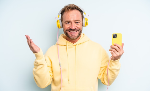 Hombre guapo de mediana edad que se siente feliz, sorprendido al darse cuenta de una solución o idea. concepto de auriculares y teléfono inteligente