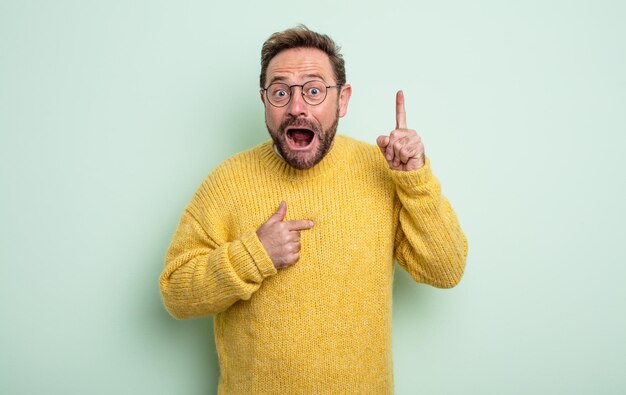 Hombre guapo de mediana edad que se siente orgulloso y sorprendido, apuntando a sí mismo con confianza, sintiéndose como el número uno exitoso