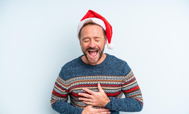 Hombre guapo de mediana edad riendo a carcajadas de una broma hilarante. concepto de navidad