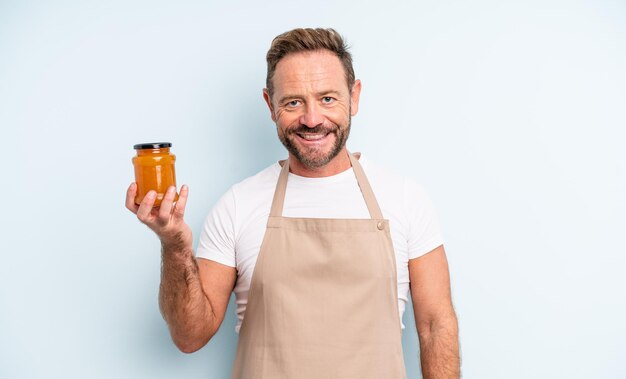 Hombre guapo de mediana edad sonriendo felizmente con una mano en la cadera y confiado concepto de mermelada de durazno