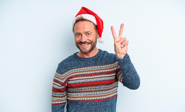 Hombre guapo de mediana edad sonriendo y luciendo amigable, mostrando el número dos. concepto de navidad