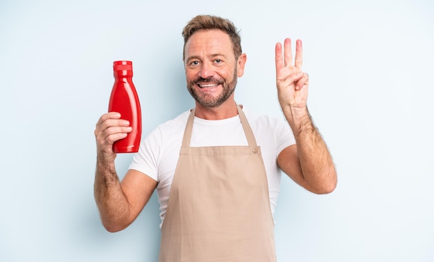 Hombre guapo de mediana edad sonriendo y mirando amigable, mostrando el número tres. concepto de salsa de tomate