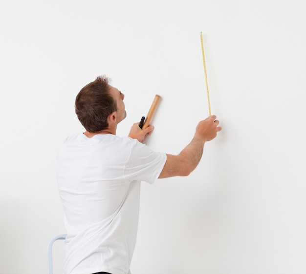 Hombre guapo mirando una pared con regla y herramientas