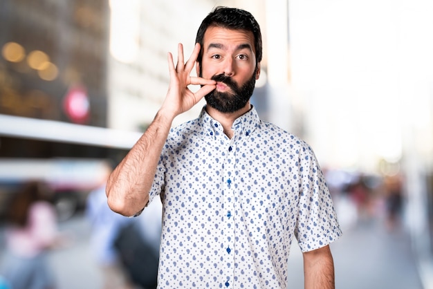 Foto hombre guapo morena con barba haciendo gesto de silencio