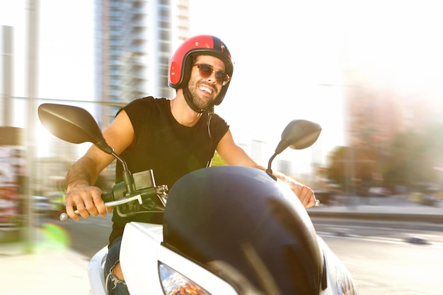 Hombre guapo en motocicleta en la ciudad sonriendo