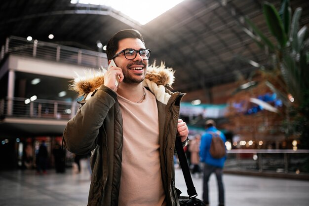 Hombre guapo con móvil en la estación de tren. Concepto de comunicación.