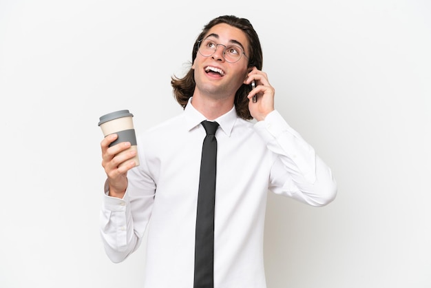 Hombre guapo de negocios aislado en fondo blanco con café para llevar y un móvil