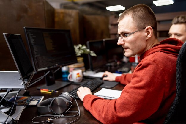 Hombre guapo ocupado trabajando con computadora en la oficina. El hombre joven tiene un trabajo de computadora.