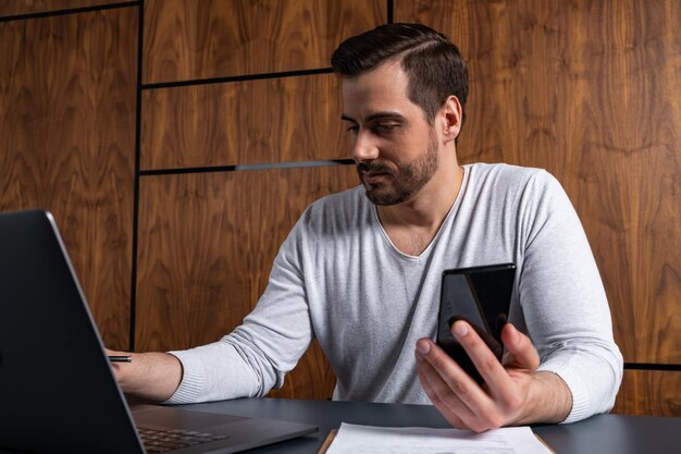 Un hombre guapo en la oficina escribiendo el contrato en la computadora portátil El concepto de buscar en Internet Ropa informal