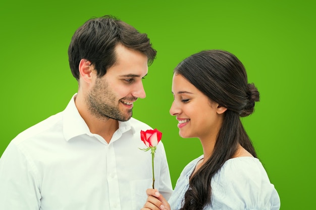 Hombre guapo ofreciendo a su novia una rosa contra viñeta verde