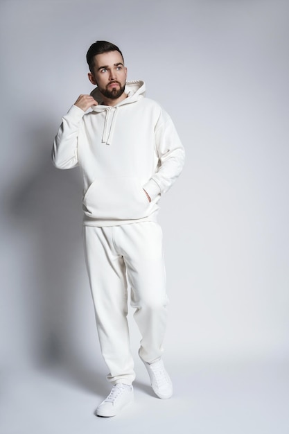 Hombre guapo con pantalones y sudadera con capucha blanca en blanco