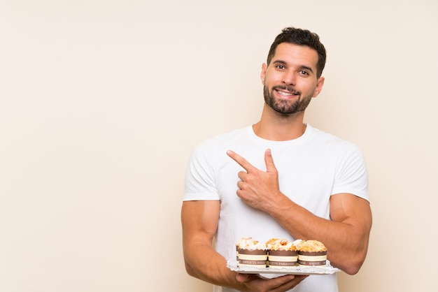 Hombre guapo con pastel de muffin apuntando hacia el lado