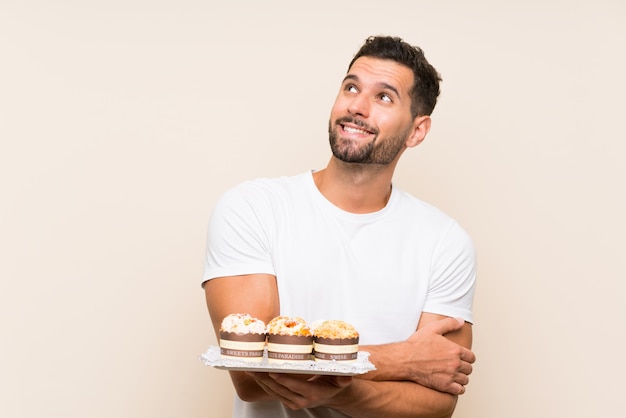 Hombre guapo con pastel de muffin sobre fondo aislado