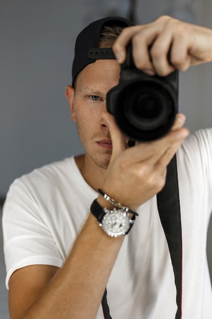 Hombre guapo con pecas sostiene una cámara digital y toma fotografías