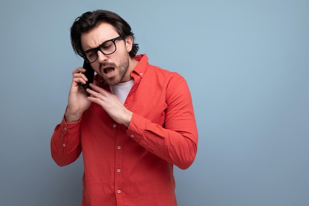 Hombre guapo de pelo oscuro con camisa roja hablando por teléfono