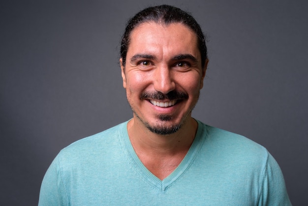 Hombre guapo con pelo rizado y bigote contra fondo gris