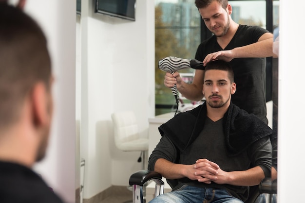 Foto hombre guapo en la peluquería secándose el cabello