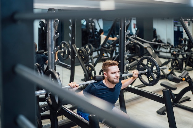 Hombre guapo practicando pesas de culturismo en el gimnasio